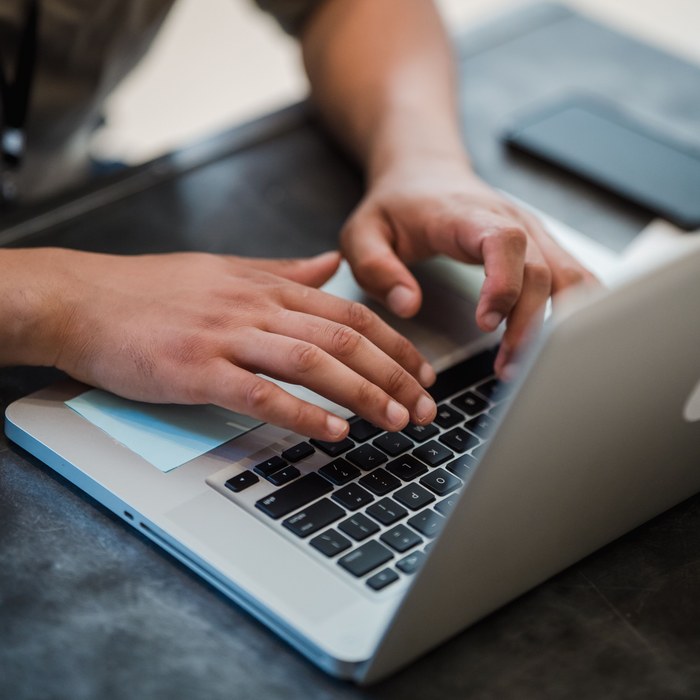 Hands typing quickly on a laptop keyboard