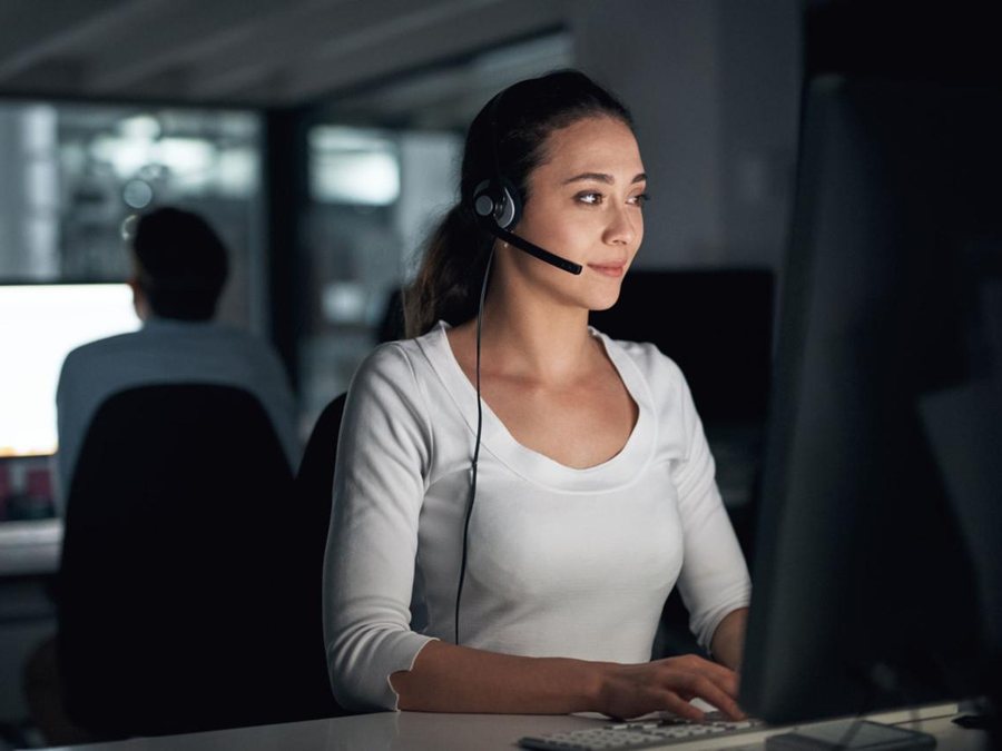 Customer service professional answering calls at a desk during an evening shift